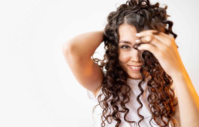 Mujer luce cabello rizado con el método curly girl